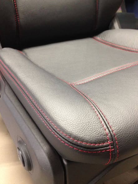 Black leather car seat with red contrast stitching